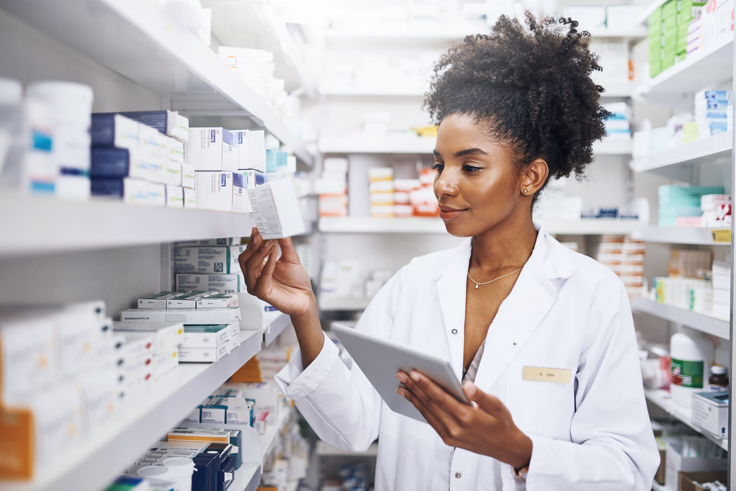 A woman in white lab coat holding tablet.