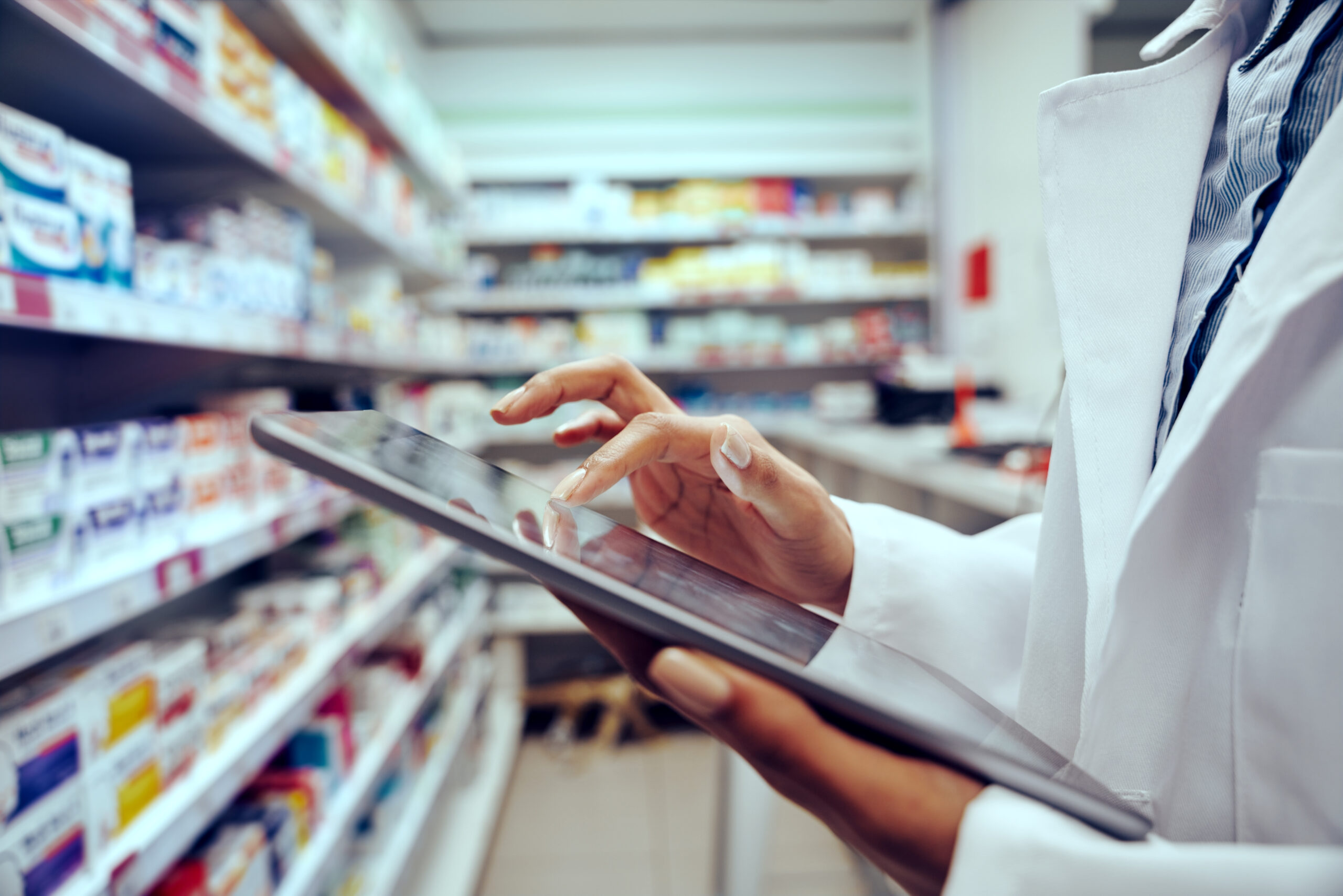 Closeup of hands of young female pharmacist checking inventory using digital tablet