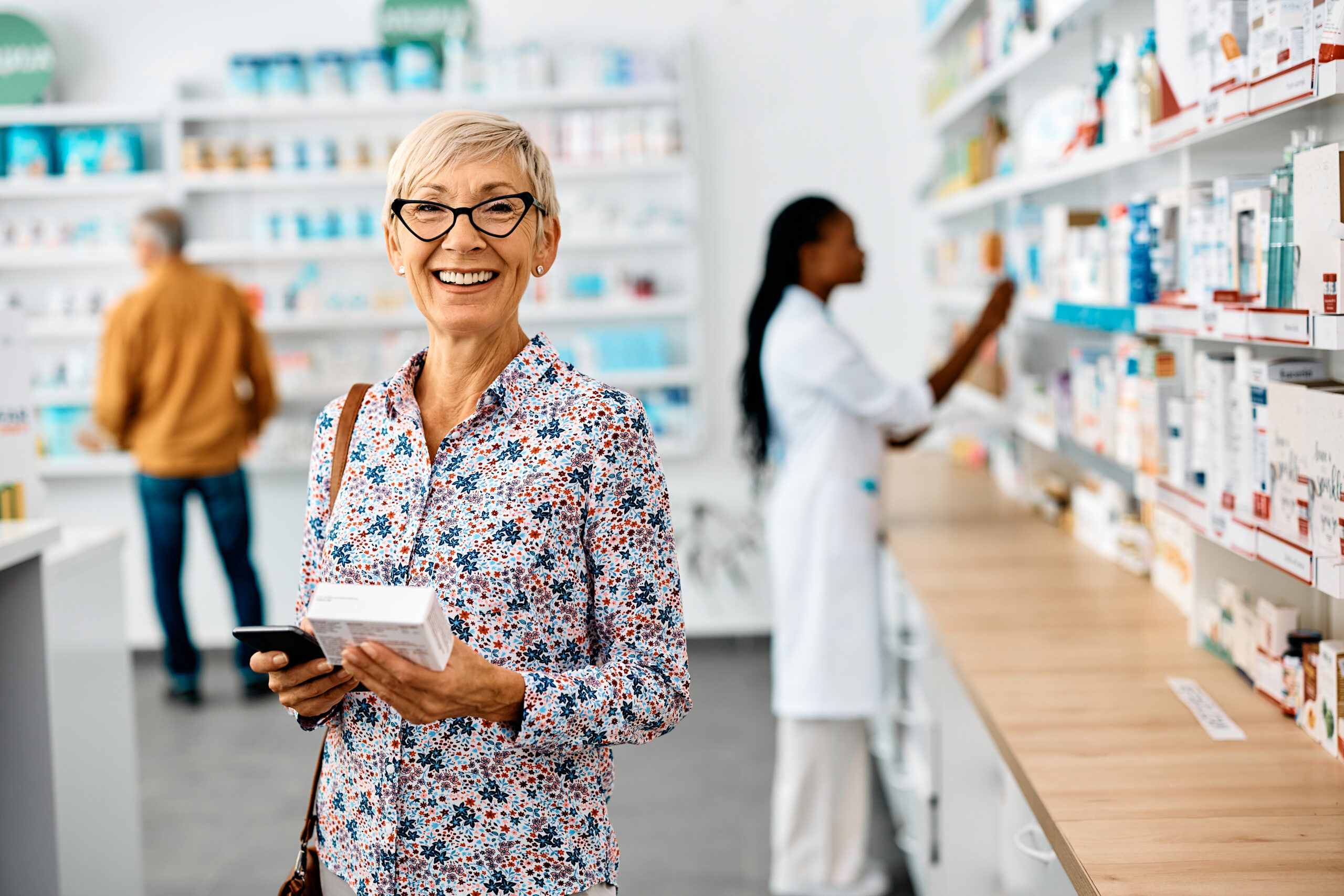 Happy mature woman shopping vitamins in drugstore and looking at camera.