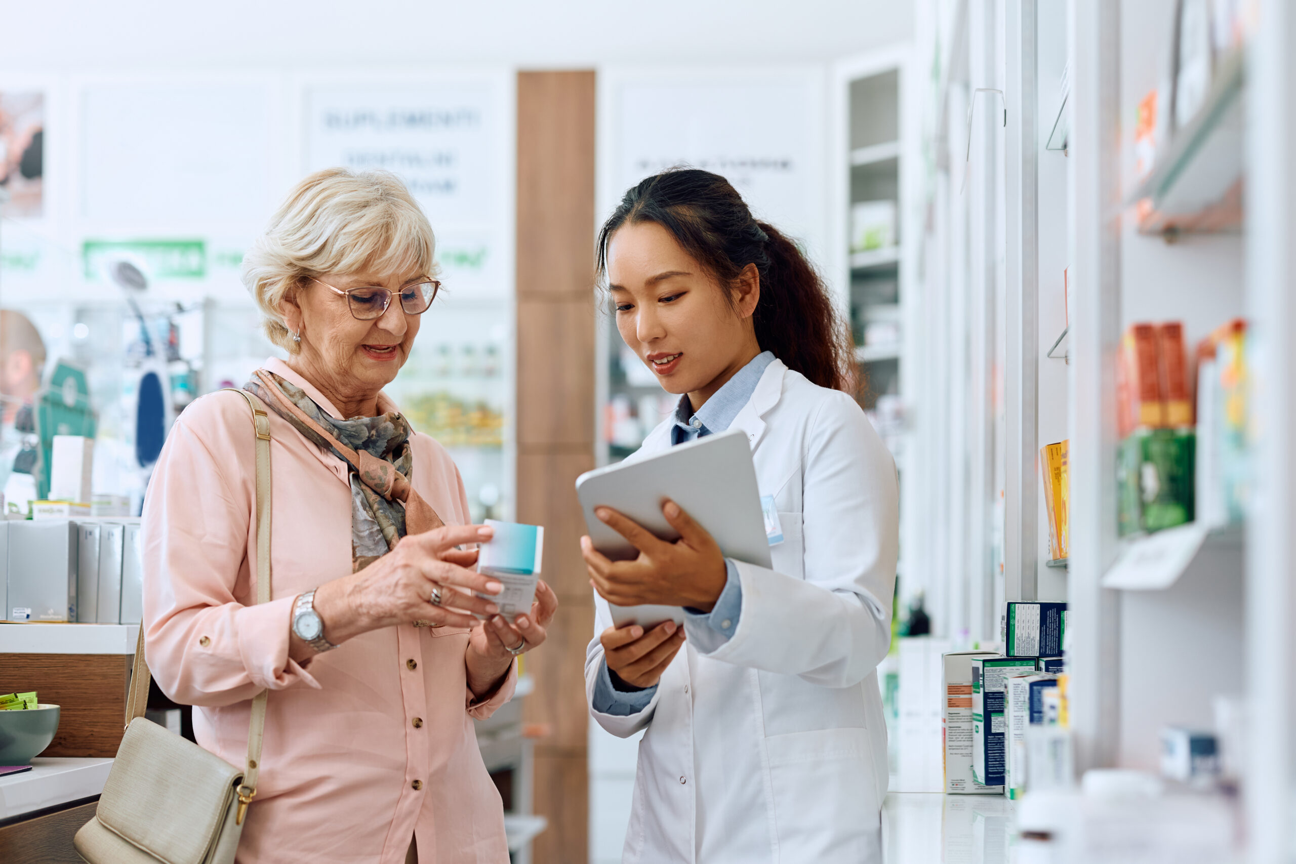 A woman and a pharmacist looking at something on her tablet.