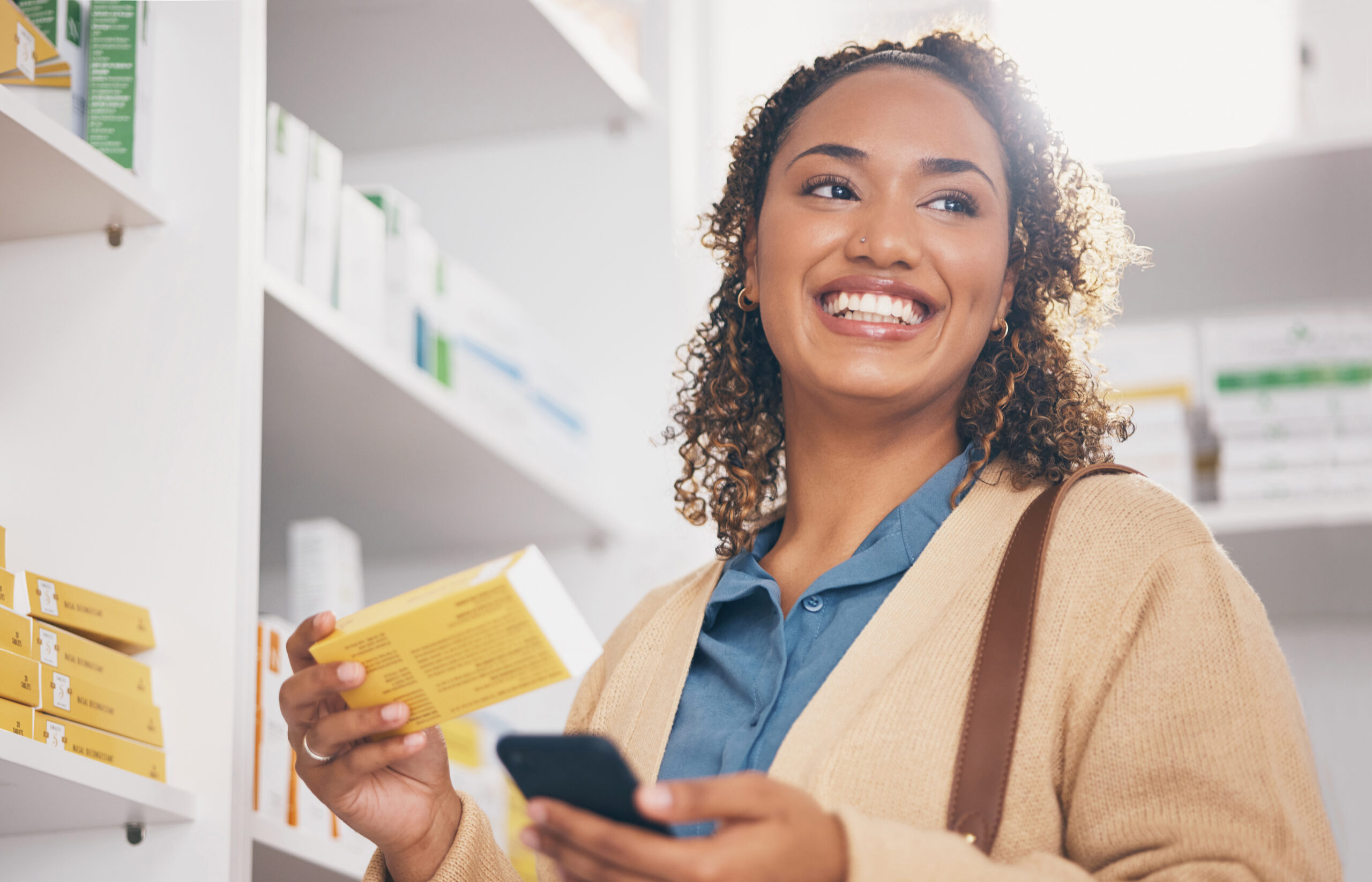 A woman holding a phone and looking at the camera.