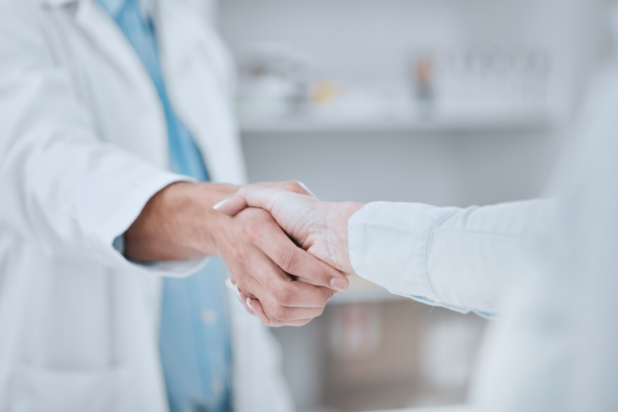 Two doctors shaking hands in a room.